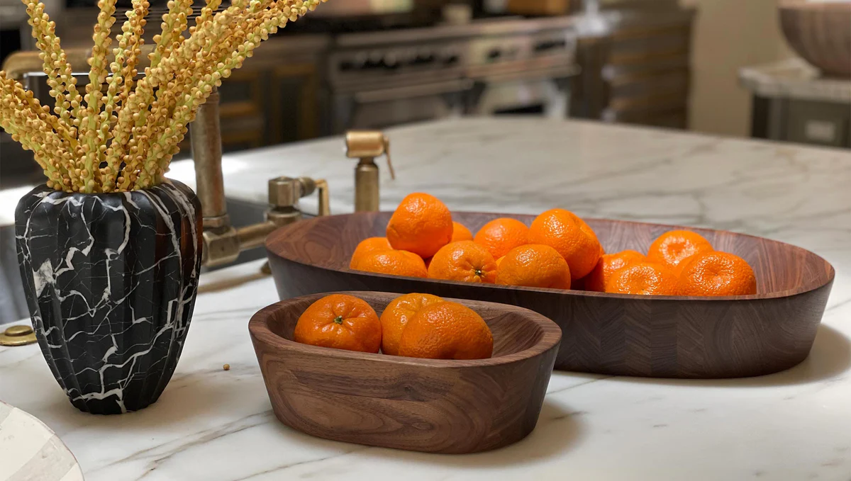 Handcrafted wooden kitchen tools on a warm worktop with bowls and natural kitchen styling